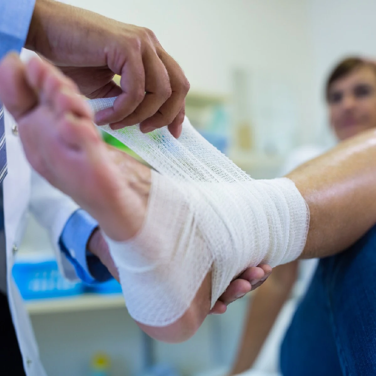 Nurse carefully dressing a patient's leg wound.